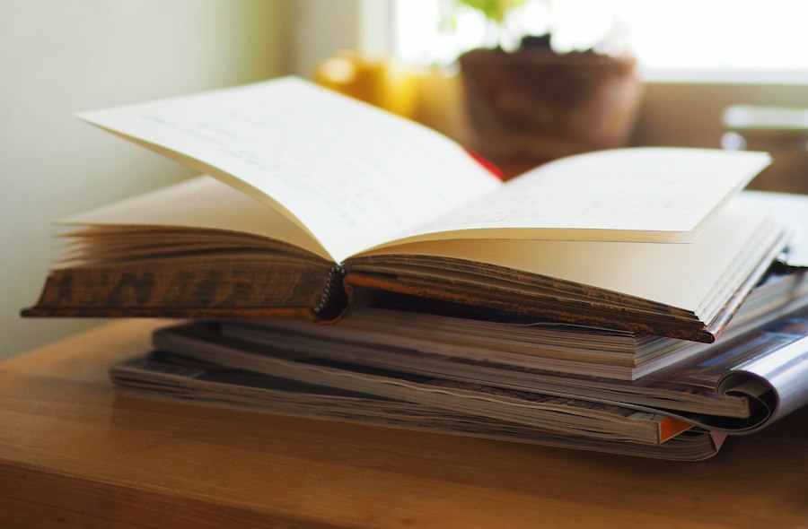 Hand writing an essay draft in a notebook beside highlighted notes